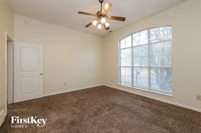 Memphis house for rent - A room with a carpet floor, a ceiling fan, and a large window with a view of trees.
