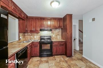 Kansas City house for rent - A kitchen with wooden cabinets and a black stove top oven.