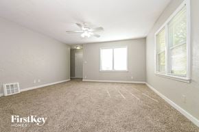 Raytown house for rent - A spacious room with a carpeted floor and a ceiling fan.
