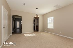 Matthews house for rent - an empty living room with a hallway to the kitchen and a chandelier