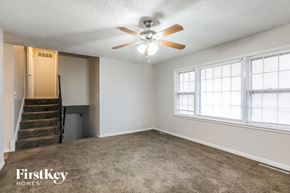 Kansas City house for rent - A spacious room with a staircase and a ceiling fan.