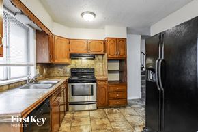 Kansas City house for rent - A kitchen with a black refrigerator and brown cabinets.