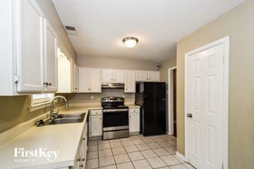 Cordova house for rent - A kitchen with a black refrigerator and white cabinets.