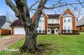 Memphis house for rent - A large tree stands in front of a brick house.