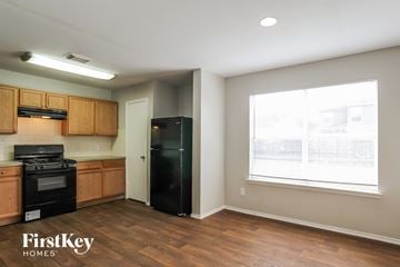Humble house for rent - A kitchen with wooden cabinets and a black fridge.