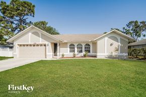 Fort Myers house for rent - a beige house with a lawn in front of it