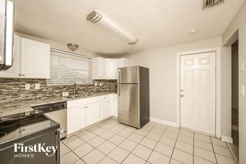 Port Richey house for rent - A kitchen with a stainless steel refrigerator and a black stove top oven.