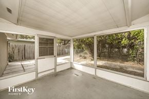 Port Richey house for rent - A room with a white ceiling and a view of a fence and trees through the windows.