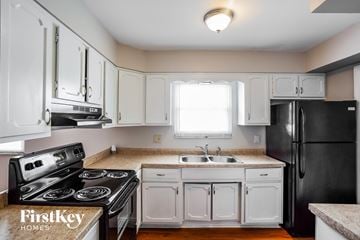 Indianapolis house for rent - A kitchen with black appliances and white cabinets.