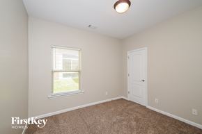 Mccalla house for rent - a bedroom with beige carpet and a white door and window