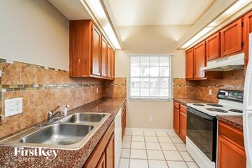 Fort Myers house for rent - A kitchen with brown cabinets and a stove top oven.
