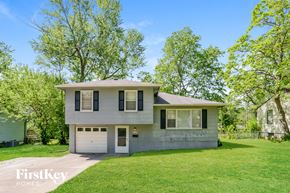 Kansas City house for rent - A two-story house with a garage is surrounded by greenery.
