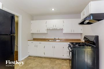 Kansas City house for rent - A kitchen with white cabinets and a black fridge.