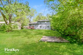 Kansas City house for rent - A house is surrounded by greenery and trees.
