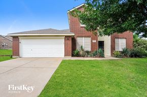 Fort Worth house for rent - A brick house with a white garage door and a tree in front.