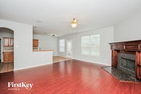 Fort Worth house for rent - A spacious living room with a fireplace and a ceiling fan.