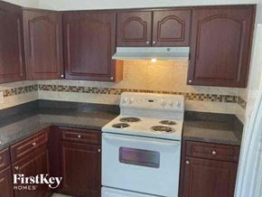 Tampa house for rent - A kitchen with a white stove top oven and brown cabinets.