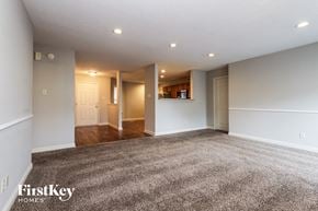 Indianapolis house for rent - A spacious room with a carpeted floor and a kitchen area in the background.