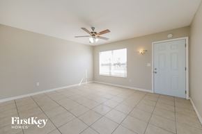 North Port house for rent - an empty living room with a ceiling fan and a white door