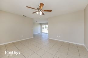 North Port house for rent - an empty living room with a ceiling fan and tiled floor