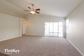 Peoria house for rent - an empty living room with a ceiling fan and a door to a patio