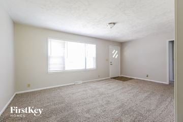 Kansas City house for rent - a spacious living room with carpet and a large window