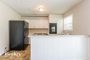 Kansas City house for rent - a kitchen with white cabinets and a counter top and a black refrigerator