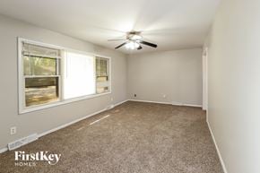 Raytown house for rent - A room with a carpet floor, a ceiling fan, and a window showing an outdoor view.