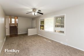 Raytown house for rent - A spacious room with a carpeted floor, a ceiling fan, and a window with blinds.