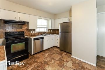 Raytown house for rent - A kitchen with a black stove top oven and a stainless steel refrigerator.