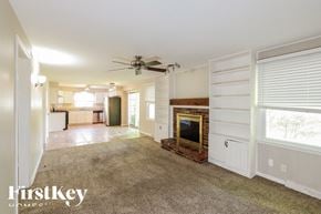 Overland Park house for rent - A spacious living room with a fireplace and a ceiling fan.