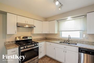 Overland Park house for rent - A kitchen with a stove top oven and a sink.