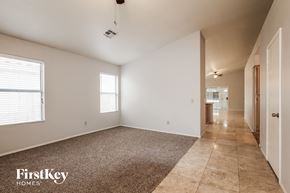 Peoria house for rent - A spacious room with a carpeted floor and a tiled floor leading to another room.