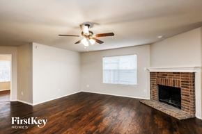 Fort Worth house for rent - a living room with a brick fireplace and a ceiling fan