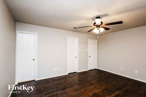 Fort Worth house for rent - a bedroom with white walls and a ceiling fan and wood floors