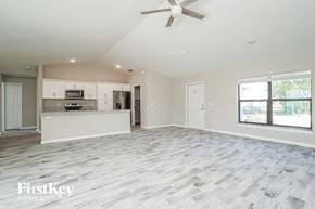 Fort Myers house for rent - an empty living room with a kitchen and a ceiling fan