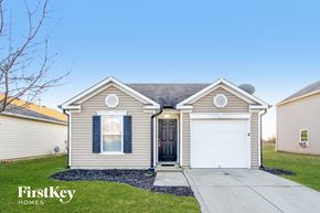 Camby house for rent - a beige house with two white garage doors and a sidewalk