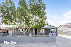 Phoenix house for rent - A house with a tree in front and a fence around it.