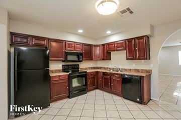 Phoenix house for rent - A kitchen with brown cabinets and black appliances.