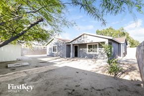 Phoenix house for rent - A house with a grey exterior is surrounded by a dirt lot and trees.