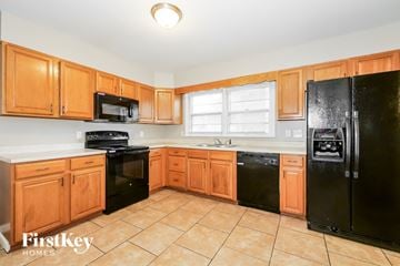 Raytown house for rent - A kitchen with wooden cabinets and black appliances.