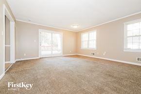 Raytown house for rent - A spacious room with a carpeted floor and a sliding glass door.