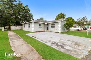 Tampa house for rent - a small white house with a driveway and grass