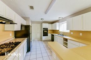 Humble house for rent - a kitchen with white cabinets and black appliances