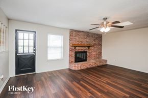 North Richland Hills house for rent - A room with a brick fireplace and wooden floors.