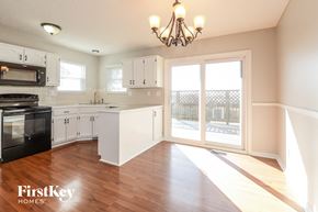 Kansas City house for rent - a kitchen with white cabinets and black appliances and a sliding glass door
