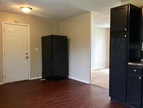 Indianapolis house for rent - an empty living room with a refrigerator and a white door