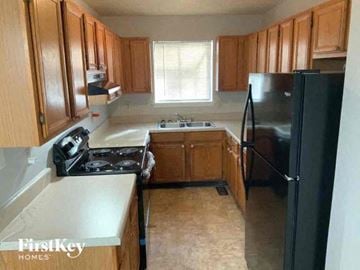 Snellville house for rent - a kitchen with wooden cabinets and a black refrigerator