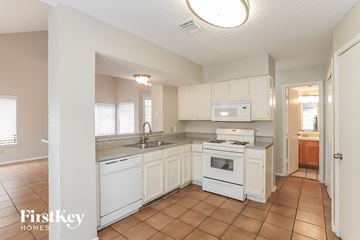 Houston house for rent - a kitchen with white cabinets and appliances and a sink