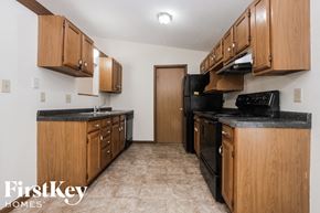 Indianapolis house for rent - an empty kitchen with black appliances and wooden cabinets